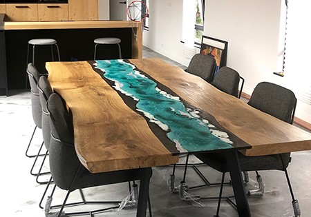 Tavolo da pranzo in legno e resina epossidica turchese, stile fiume, con sedie moderne in un interno contemporaneo.