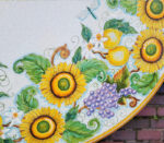 Tavolo in ceramica dipinto a mano con girasoli, limoni, uva e una libellula, stile mediterraneo.
