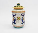 Vaso in ceramica dipinto a mano con motivi floreali blu, arancioni e gialli, su sfondo bianco.