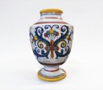 Vaso in ceramica dipinto a mano con motivi floreali e colori vivaci, su sfondo bianco.